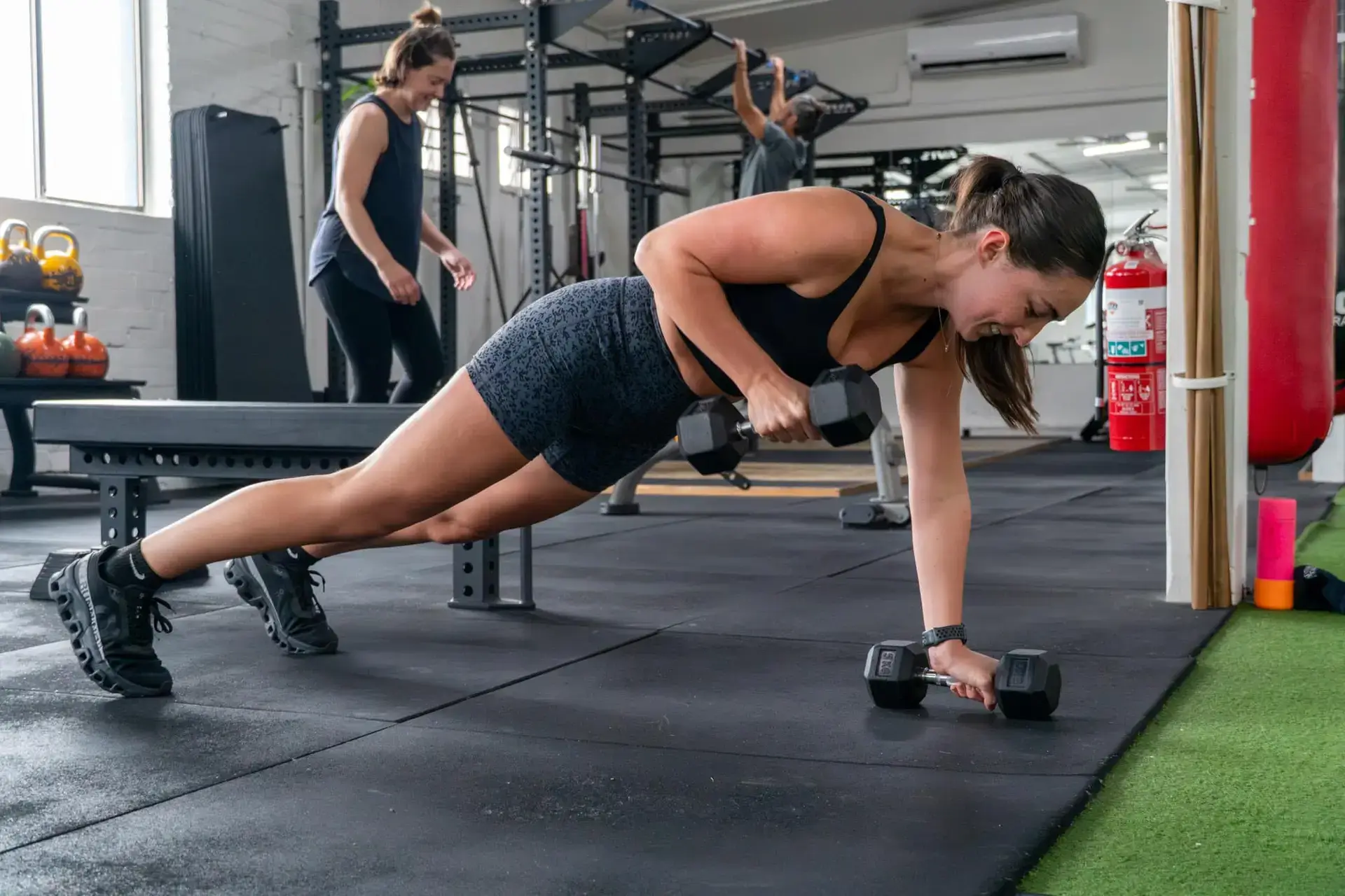 A woman performs a renegade row with dumbbells at Catalyst Training Co. gym in Randwick.