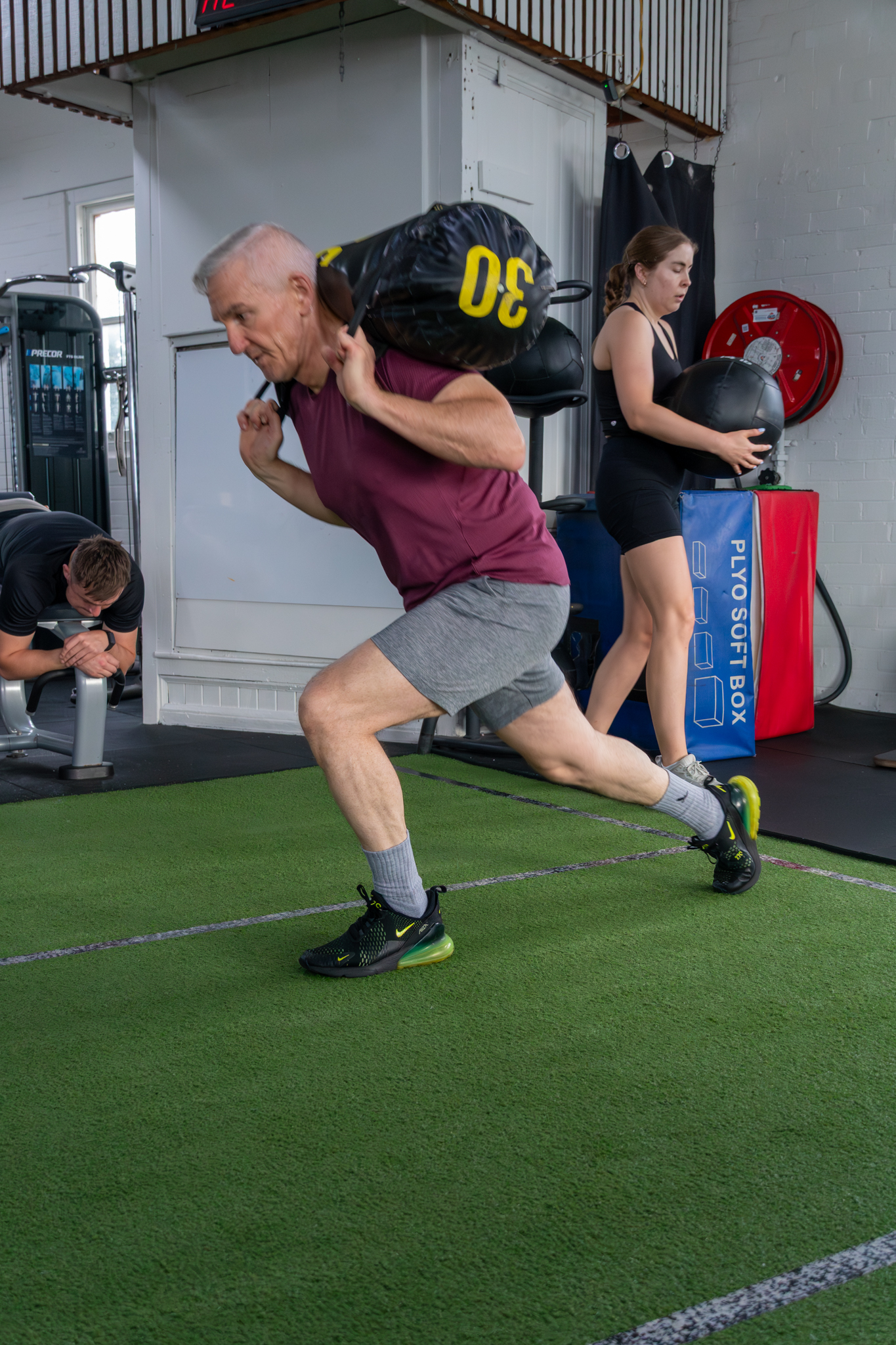 A Catalyst member doing a sandbag reverse lunge on the turf at the gym in Randwick