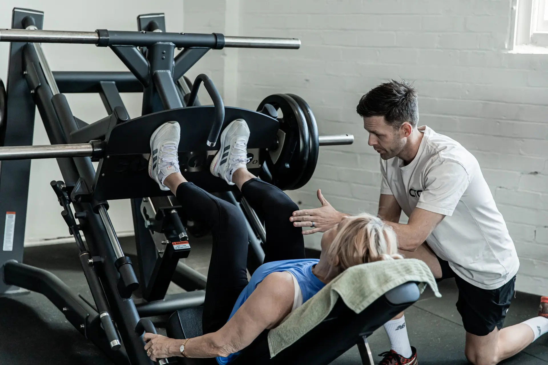 Strength training for women over 40: a Catalyst coach beside a member on the leg press in Randwick