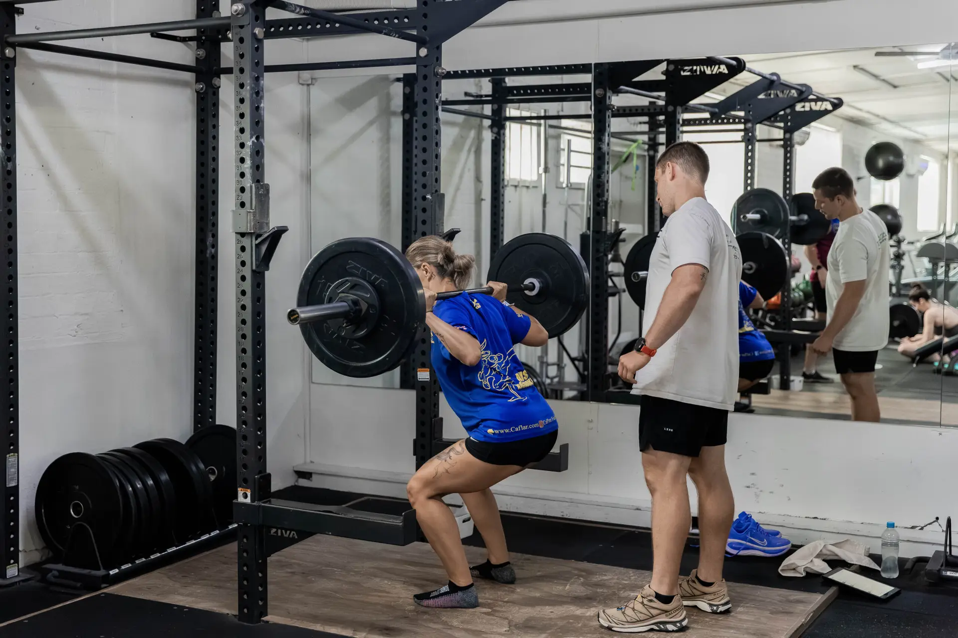 A Catalyst member back squatting with a coach spotting at Catalyst Training Co Randwick