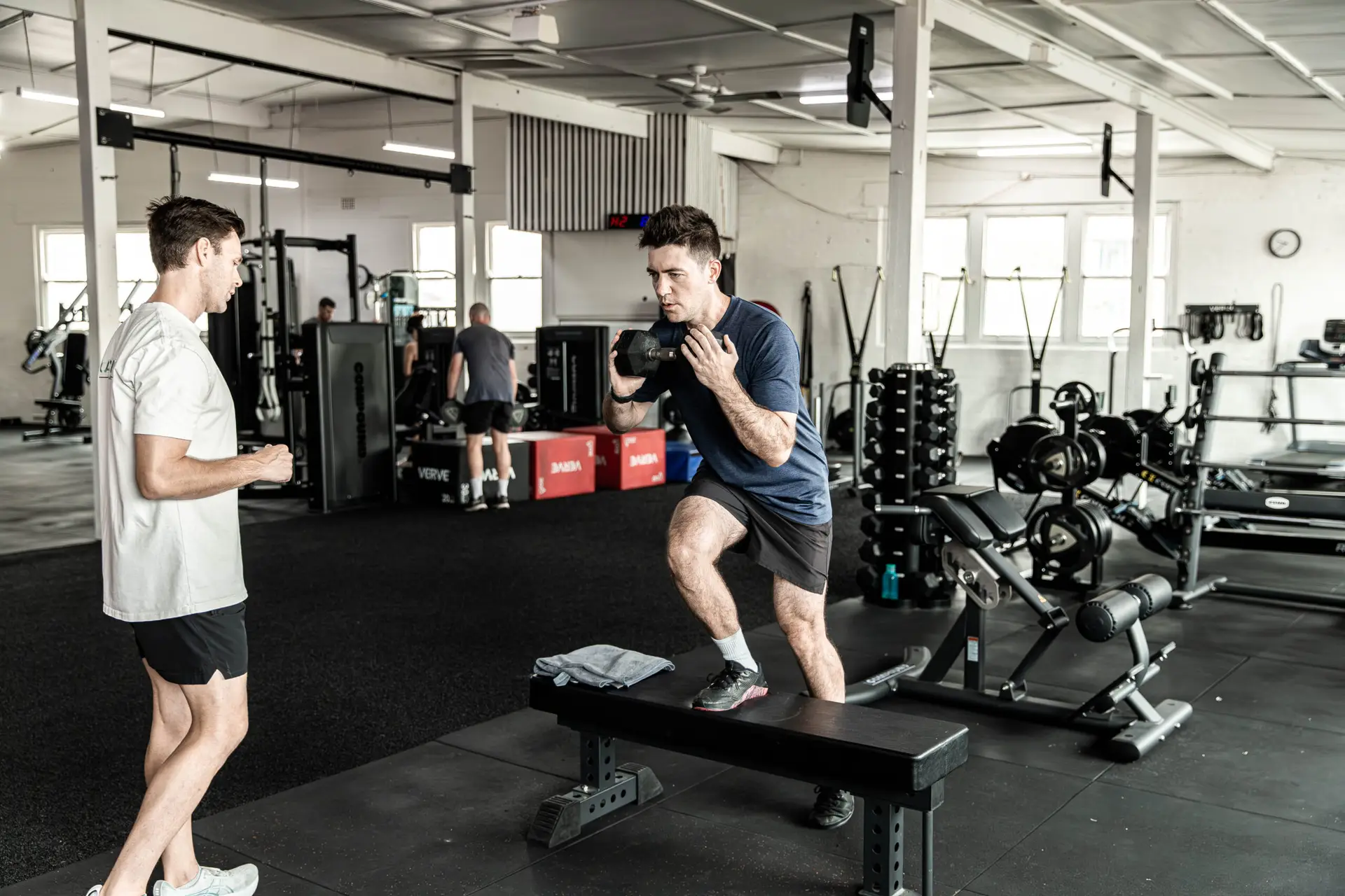 A Catalyst coach watching a client do split squats during a personal training session in Randwick