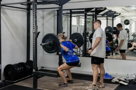 A Catalyst member back squatting with a coach spotting at Catalyst Training Co Randwick