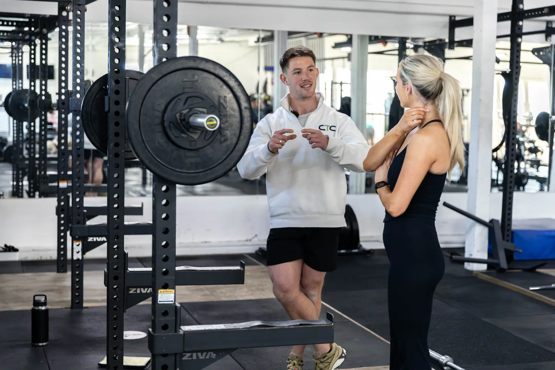 A Catalyst coach talking a client through her training plan on the gym floor