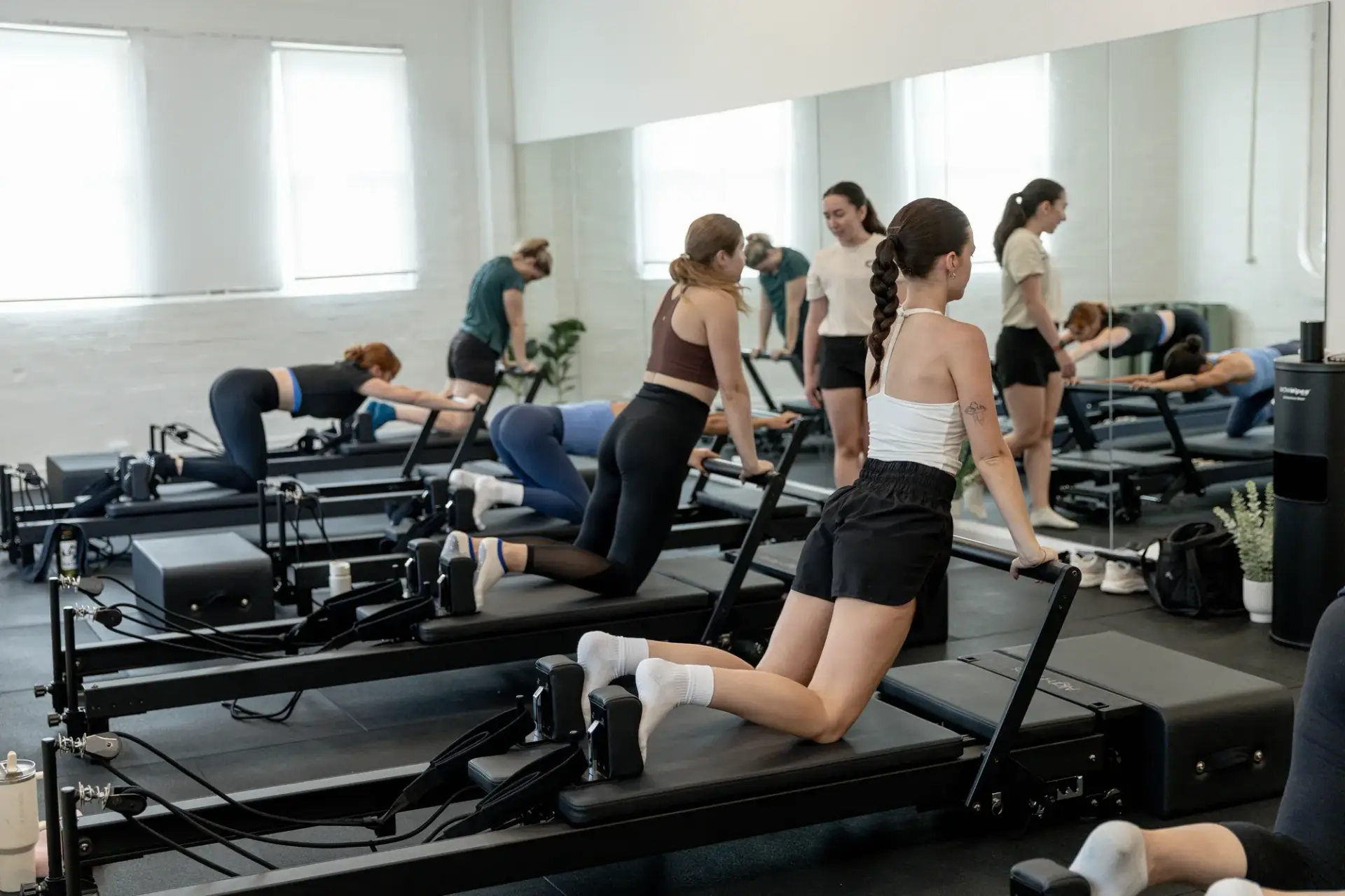 Pilates instructor correcting form during a reformer class