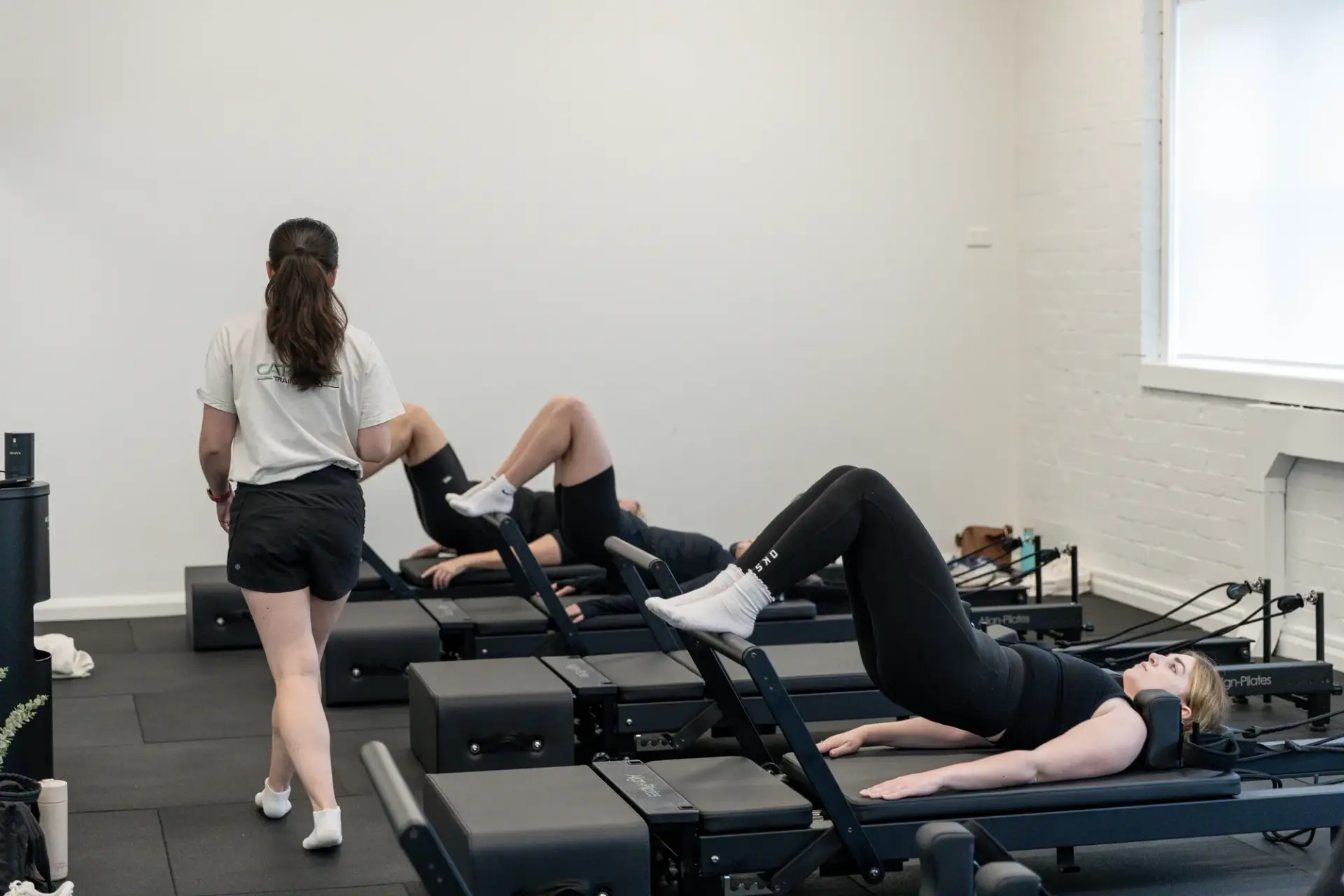 Pilates instructor beside a client during a small group reformer class in Randwick